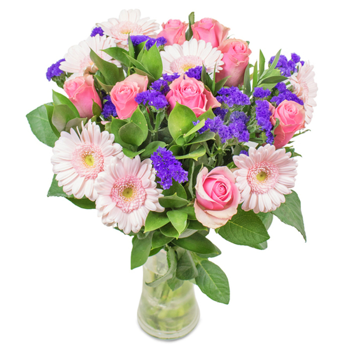 In this strikingly arranged bouquet by Florist Berrylands, a clear glass vase frames a harmonious gathering of colour and texture inspired by the area's lush suburban gardens. At the heart, about 7-9 pink roses present their tightly wrapped spirals and unfolding beauty, each bloom radiating classic affection. Encircling the roses, 5-7 pale pink gerbera daisies fan out their abundant petals, each flower echoing the soft light that filters through Berrylands' tree-lined streets. Clusters of vivid purple statice add energy, depth, and a playful counterpoint, much like the wild growth seen in local nature spots. The foundation is a generous swath of glossy greenery, whose freshness suggests longevity and care, much as you'd expect from a bouquet delivered by a trusted local florist. With its visible stems and water sparkling within the vase, the arrangement feels vibrant and alive, making it a perfect gift for occasions like birthdays, anniversaries, or as a heartfelt gesture at home or in an office near Berrylands station. Every facet of this creation is a celebration of joy, thoughtful design, and the welcoming spirit of Berrylands.